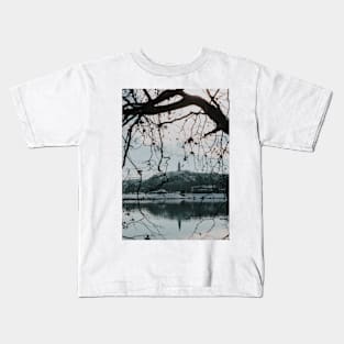 Branches of trees in front of church tower with river bank. Kids T-Shirt